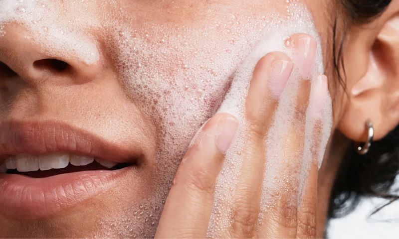 woman applying Neutrogena® Evenly Clear™ Acne Cleanser to face
