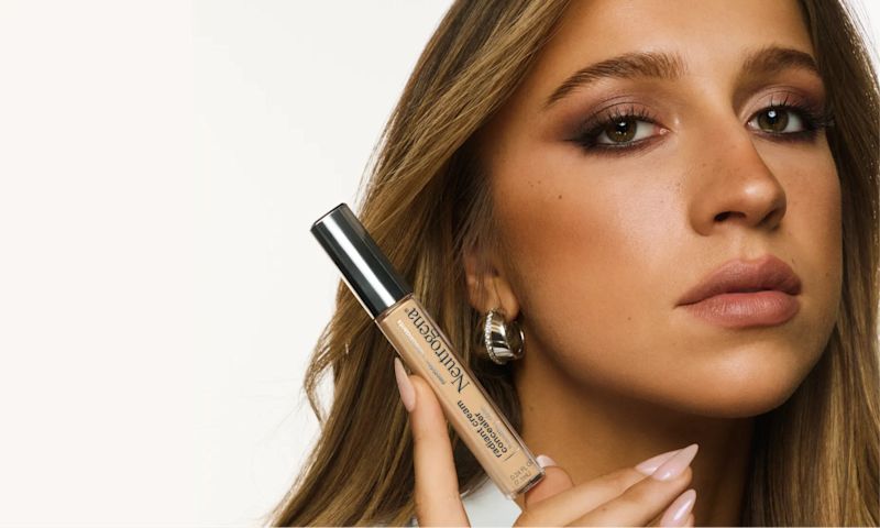 Tate McRae holding a bottle of Neutrogena® Healthy Skin radiant cream concealer
