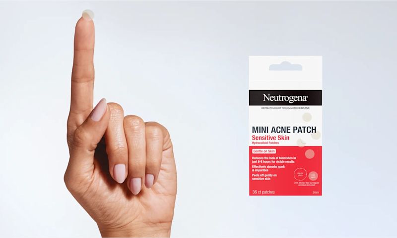 A fingertip holds up a clear acne patch next to a package of Neutrogena Mini Acne Patches for Sensitive Skin.