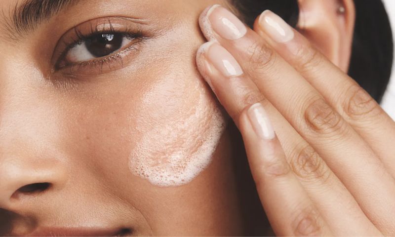 Woman with healthy skin applying Neutrogena® Gel Cleanser to her face