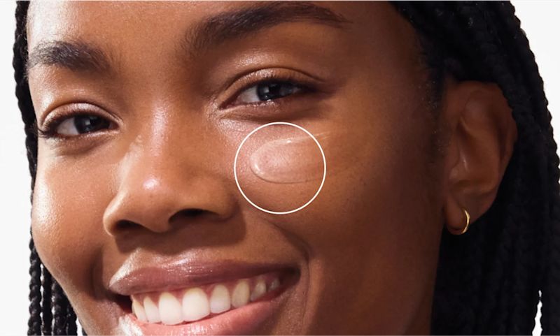 woman smiling applying Neutrogena Ultra Sheer Invisible Gel Face Sunscreen Broad Spectrum SPF 40, 1.7 Oz to cheek