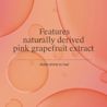 Text that reads “Features naturally derived pink grapefruit extract” and “Adds shine to hair,” over a peach background with abstract liquid bubbles.