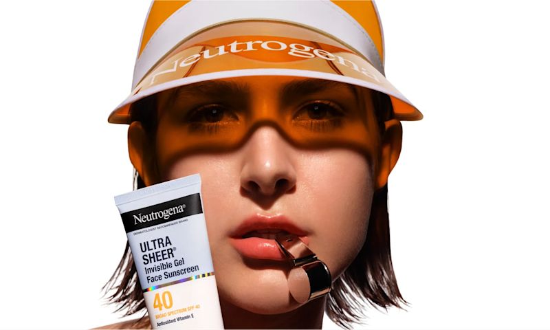 Woman wearing a visor and a tube of Neutrogena® Ultra Sheer Invisible Gel Face Sunscreen Broad Spectrum SPF 40, 1.7 Oz