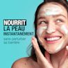 Une jeune femme se lavant le visage avec un nettoyant moussant tout en souriant.