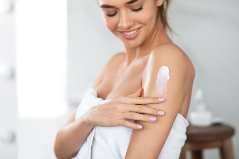 Junge Frau trägt Bodylotion auf Ihre Haut auf