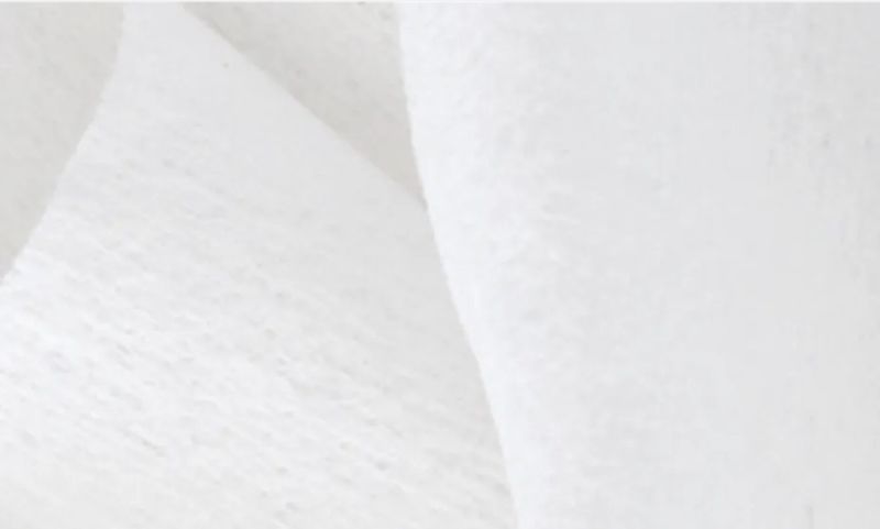 Close-up of a white, textured non-woven fabric, such as a wipe, gauze, or insulation material.