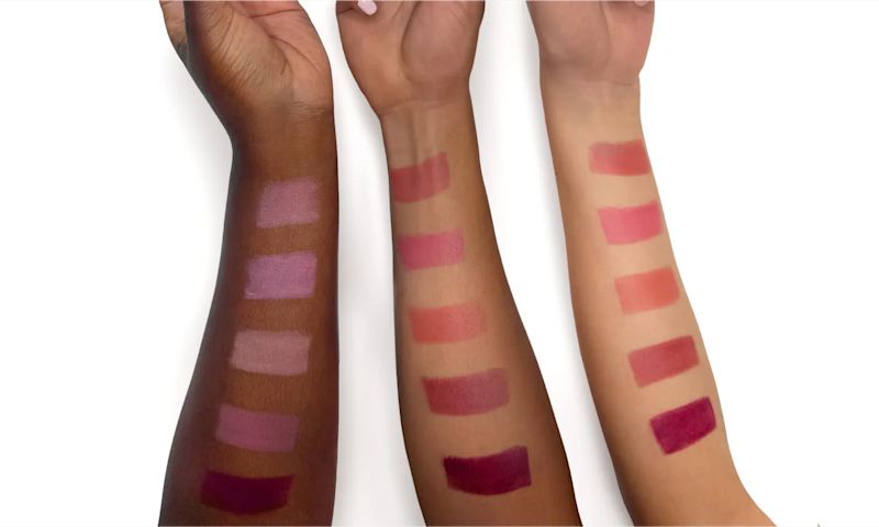 Hands of different skin tones holding up Neutrogena® Healthy Glow Blush Stick shades with swatches against different skin tones