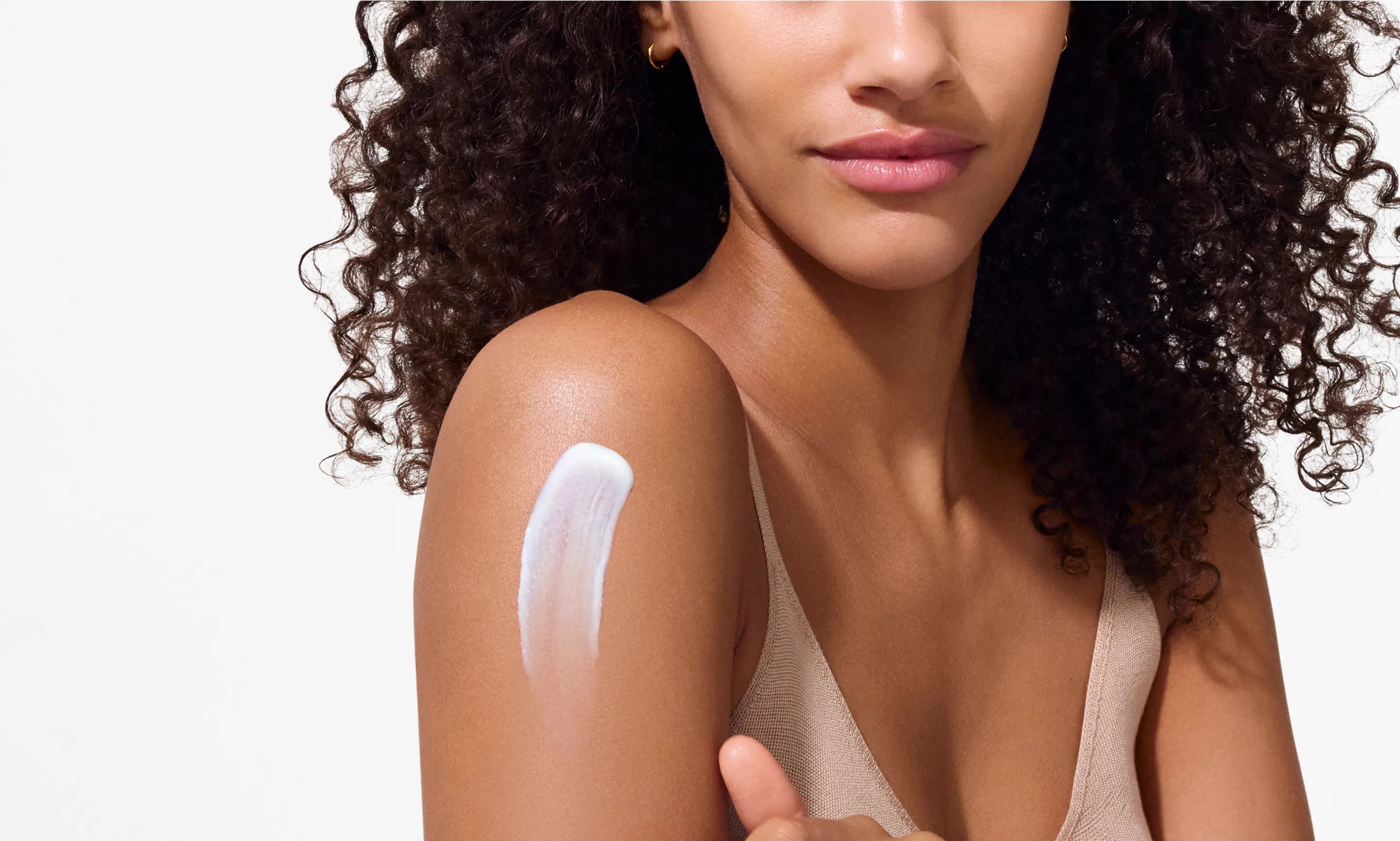 woman applying lotion to shoulder