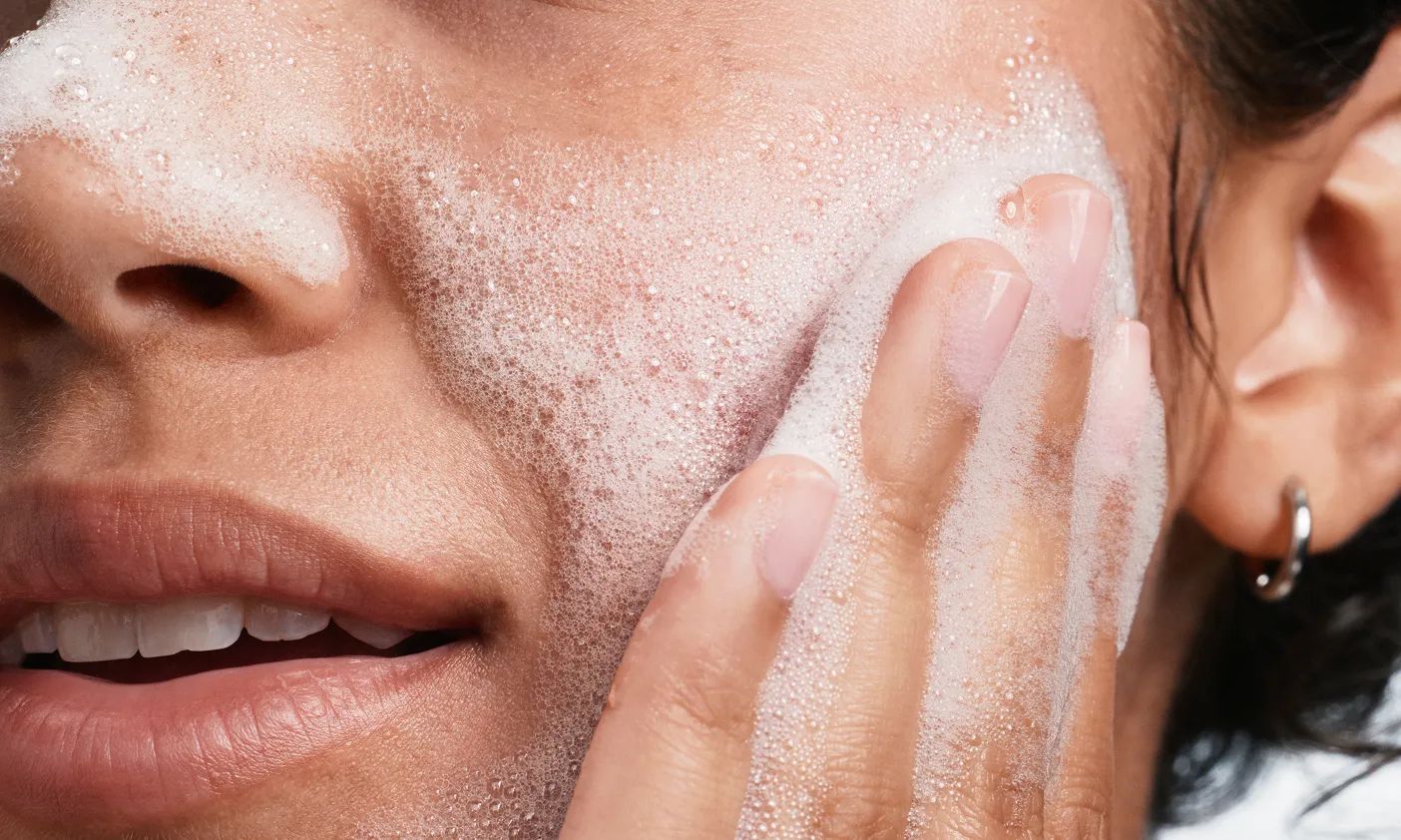 woman using a Neutrogena® facial cleanser to lather skin