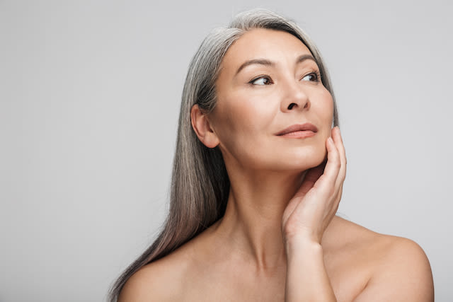 Mujer madura con canas luce su piel luminosa