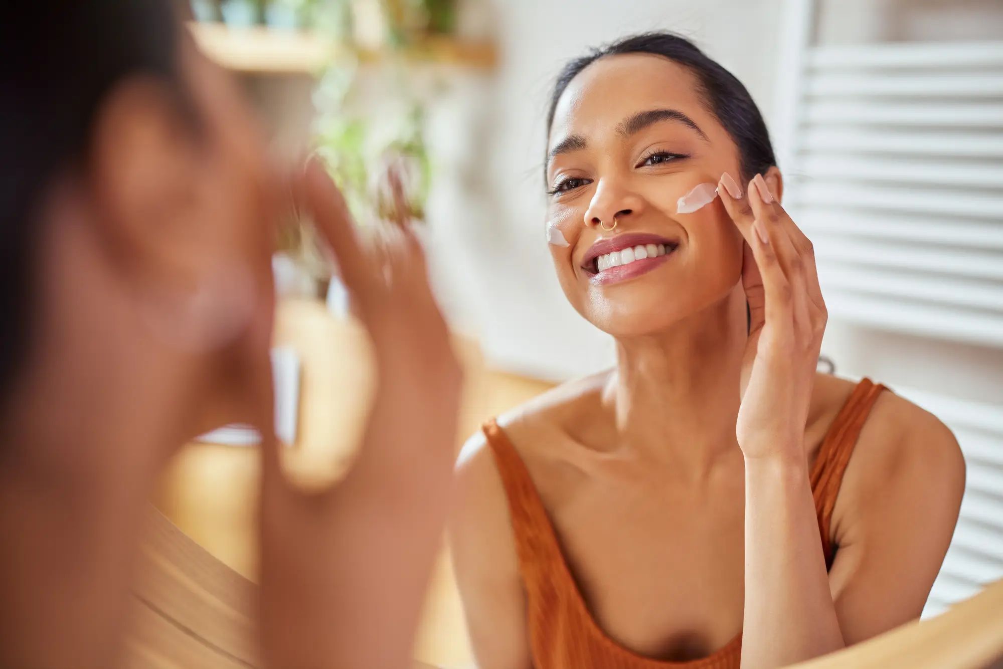 Mujer sonriente aplicándose retinol para estimular la producción de colágeno natural