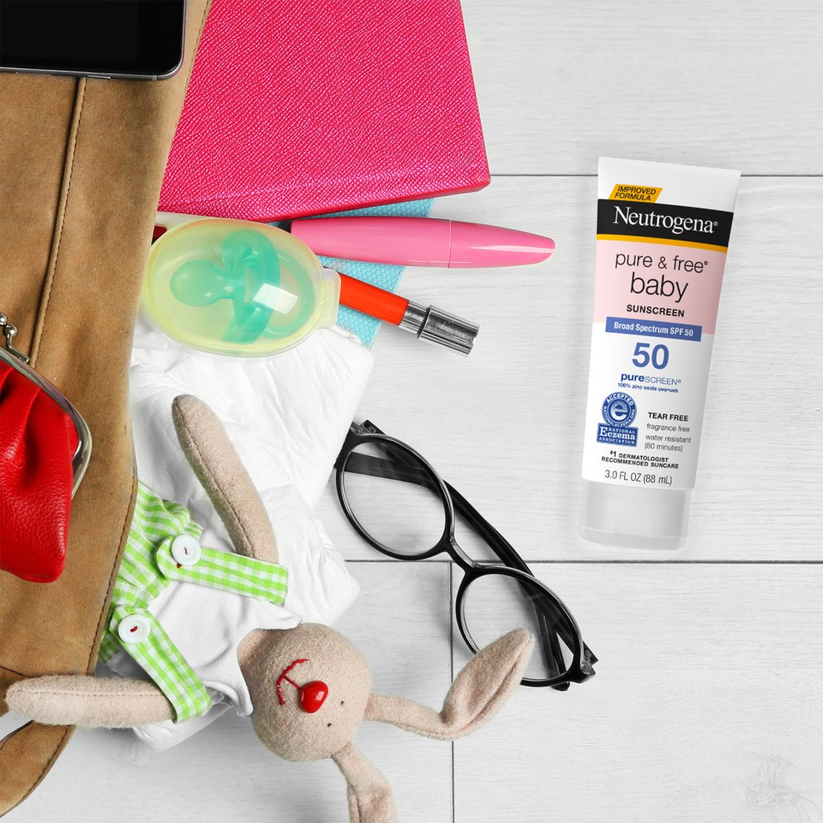 Baby travel bag essentials with Pure & Free baby sunscreen SPF 50 tube on tile floor