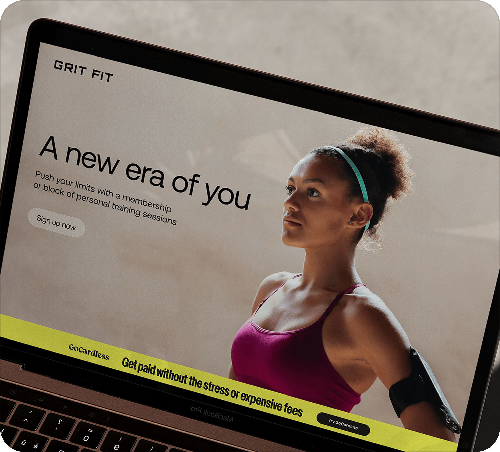A laptop screen showing a gym website with a woman in gym clothes and the title "A new era of you" with an example of one of the banners from the toolkit at the bottom of the screen that says "Get paid without the stress or expensive fees"