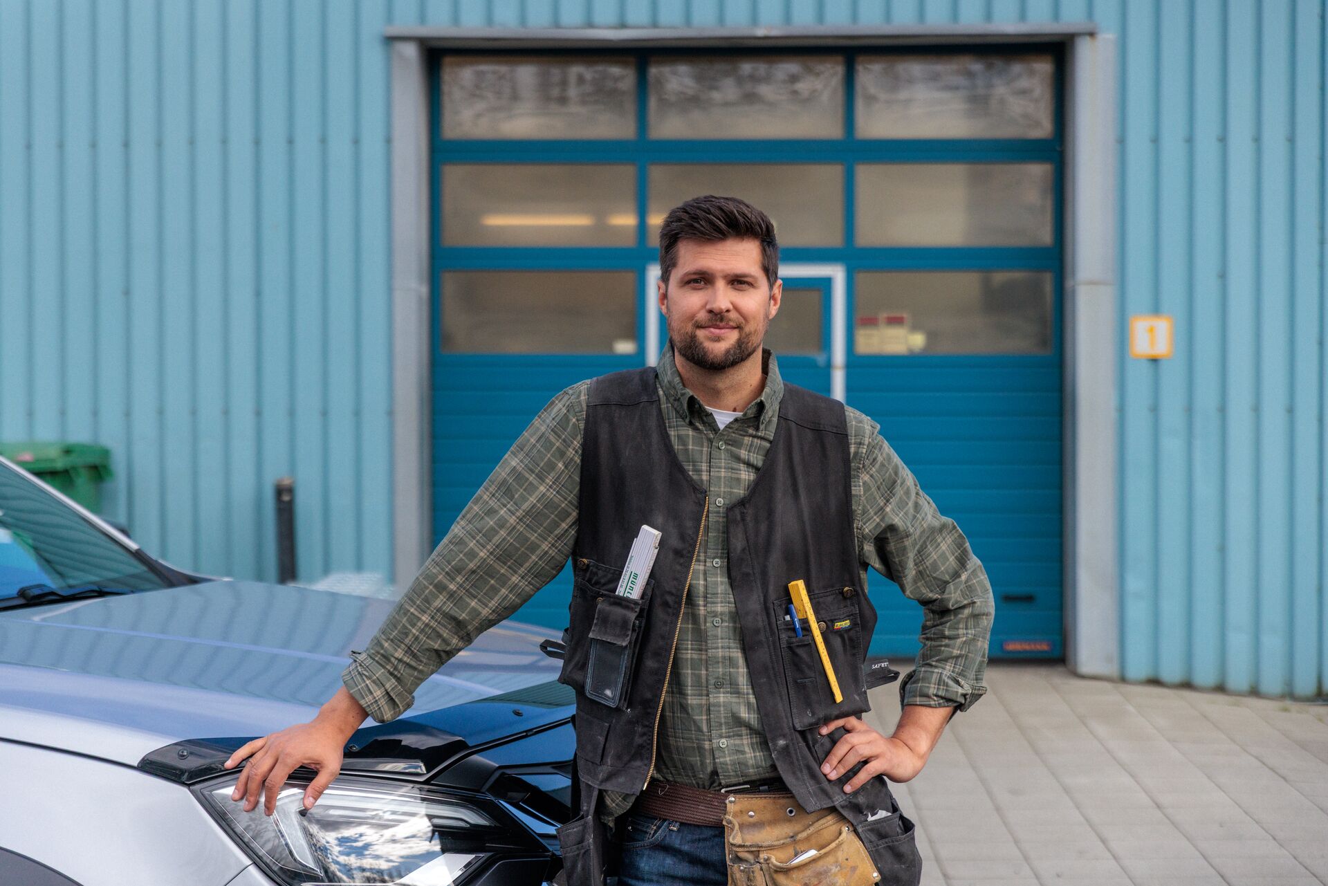 Smiður með hendina á bíl