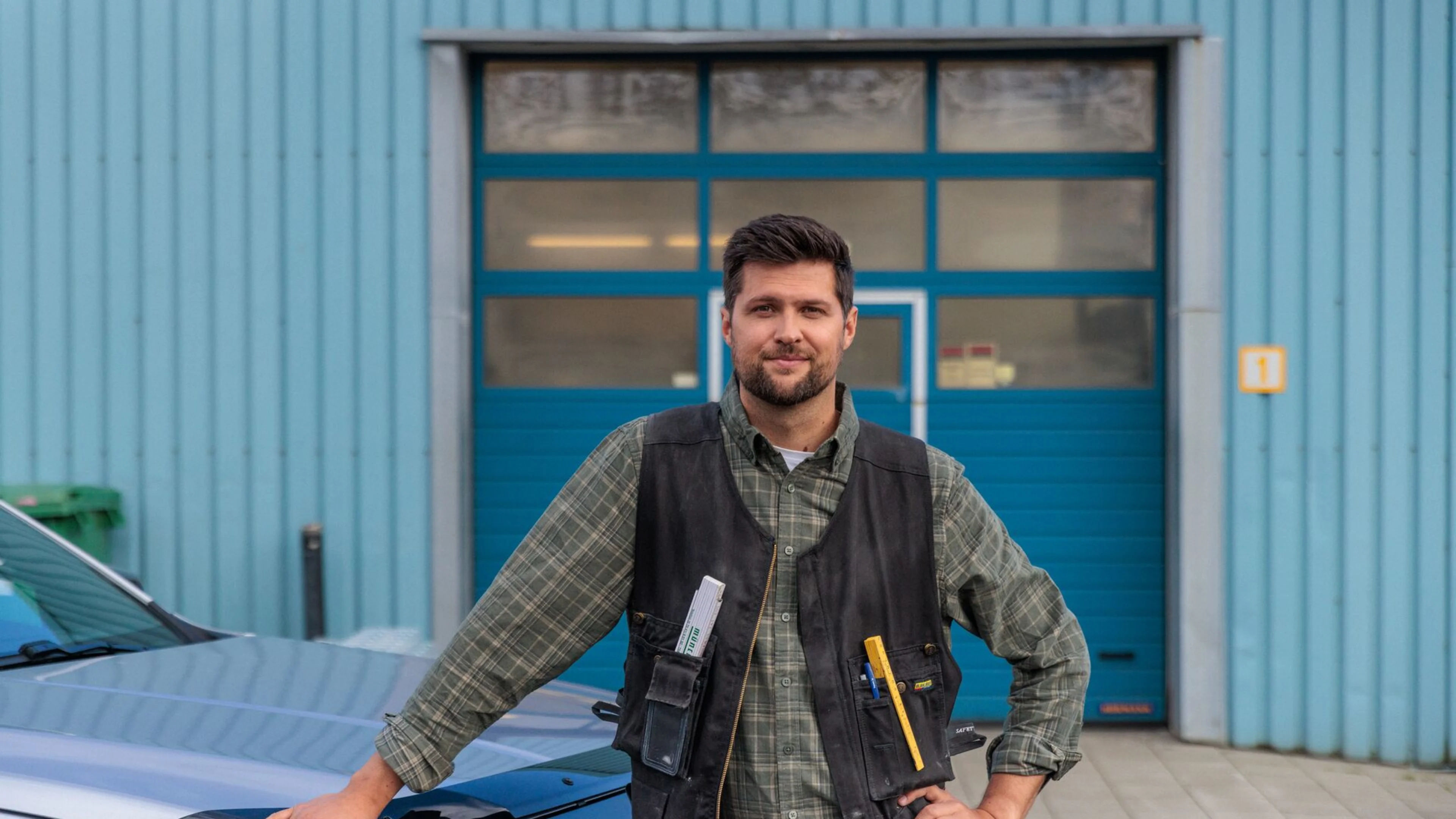 Smiður með hendina á bíl