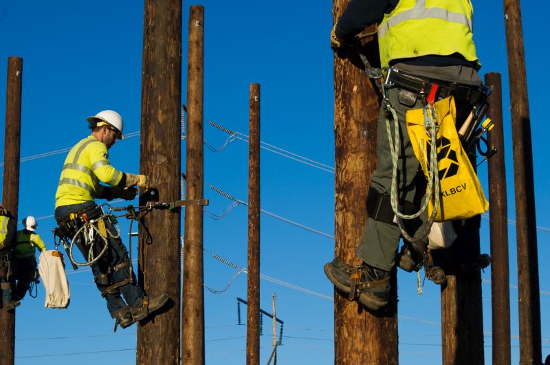 Multiple pre-apprentices with PGE climbing power poles during a line crew training event
