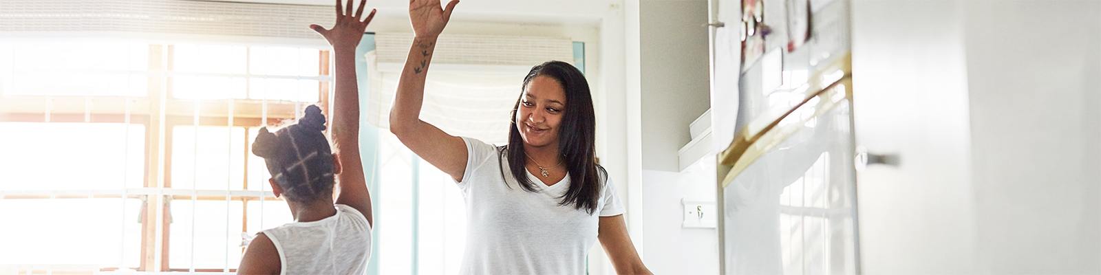 Mom and daughter high-fiving in the kitchen because they're saving money with PGE energy shifting programs