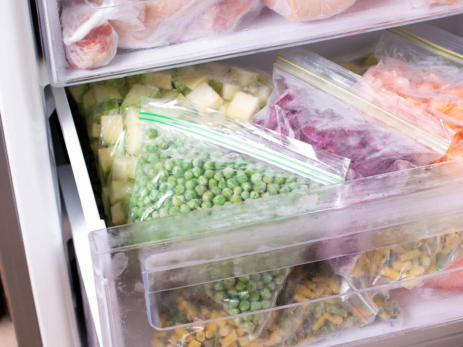 A freezer packed with veggies and food in an efficient way to keep warm air out and food cool. Image on text says: Energy Saving Hacks. Pack your freezer. A full freezer is an efficient freezer. All those frozen items will help cool down any warm air that sneaks in when you're getting something out of it.