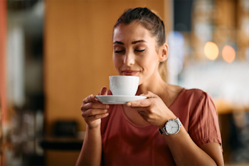 Mujer oliendo una taza de café