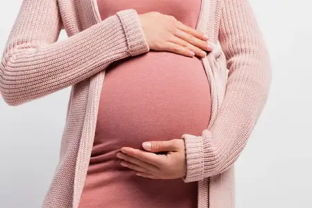 Mujer embarazada sosteniendo su vientre con ambas manos.