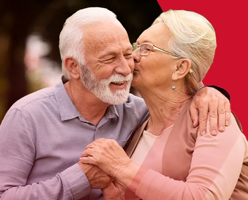 Pareja de adultos mayores abrazándose y sonriendo.