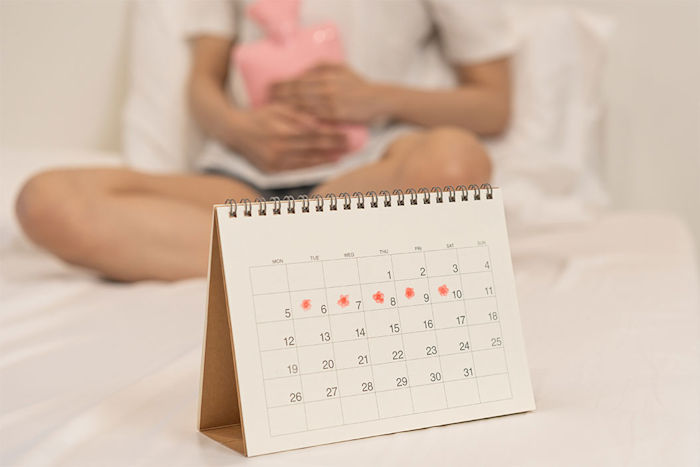 Calendario con fechas mercadas y una embarazada en el fondo