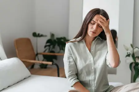 Mujer con dolor de cabeza, síntoma frecuente de anemia por deficiencia de hierro.