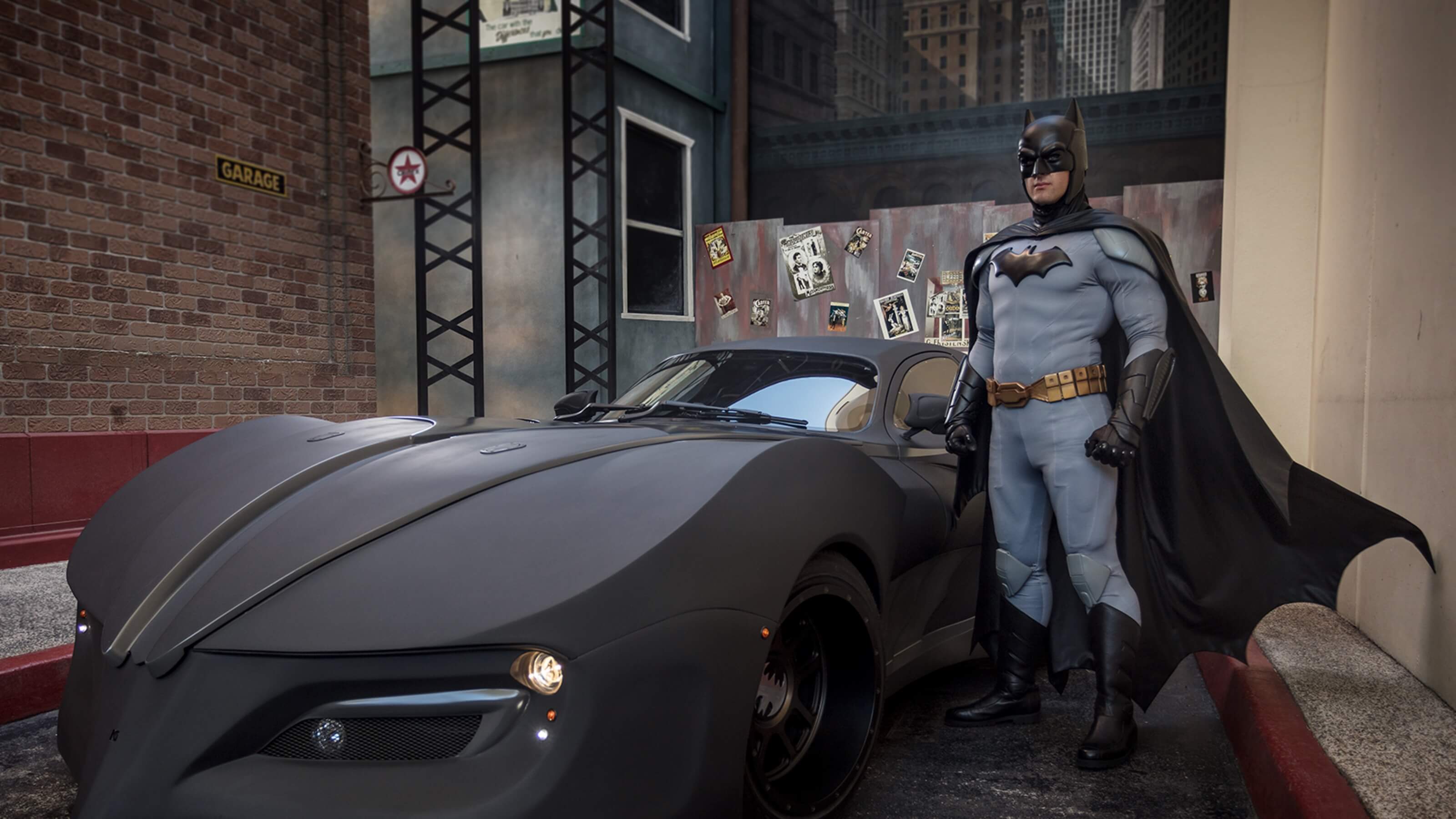 Batman standing next to the JL 52 Batmobile at Warner Bros. Movie World