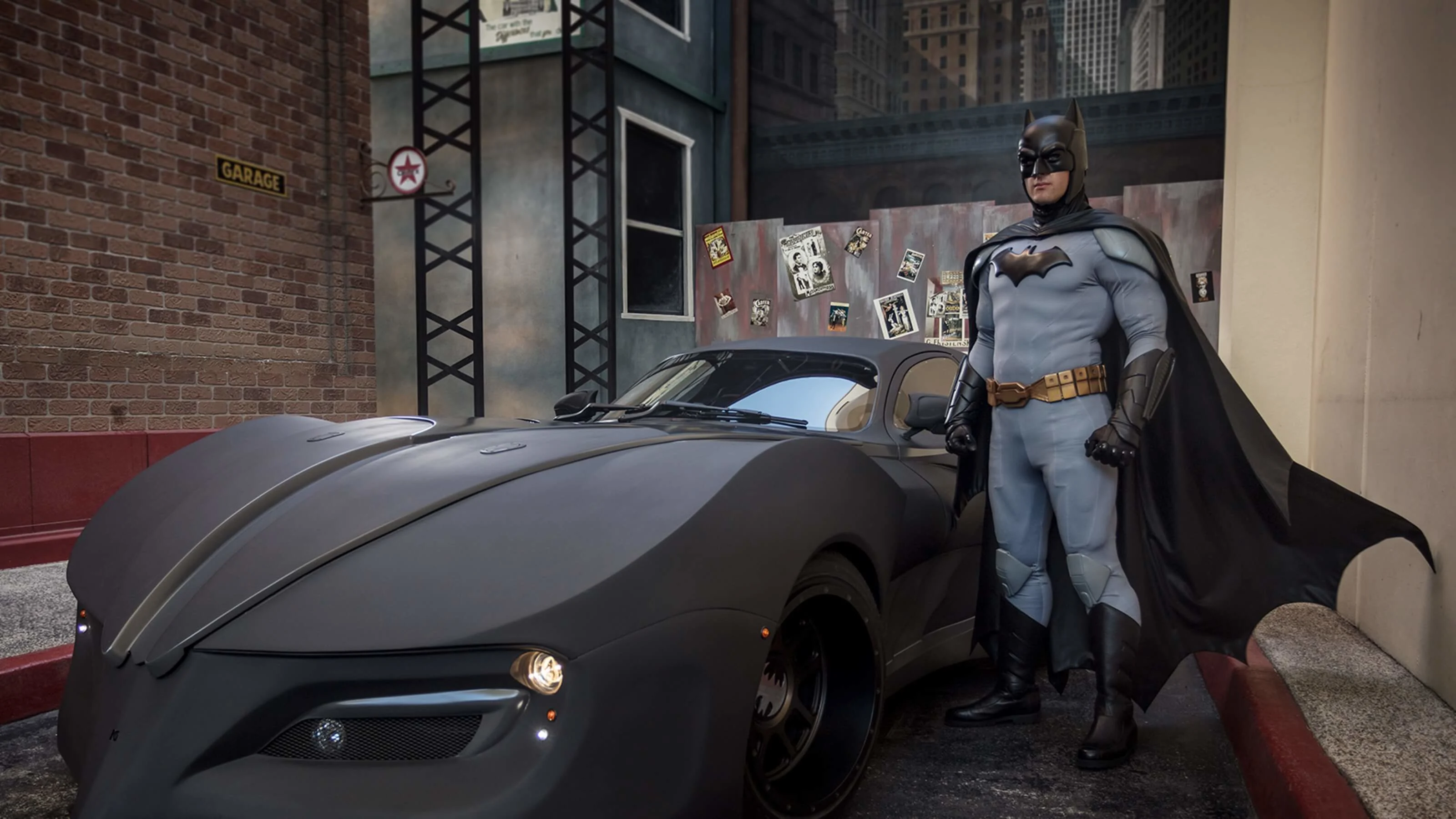 Batman standing next to the JL 52 Batmobile at Warner Bros. Movie World