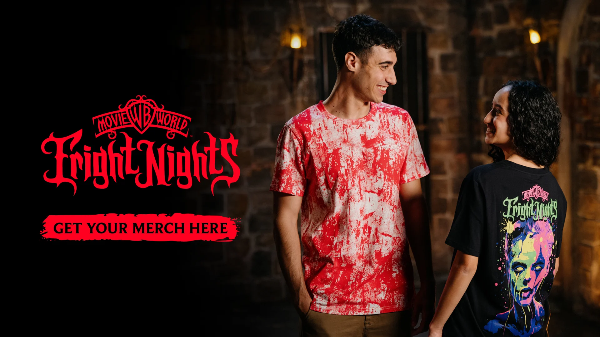 Two people stand against a stone wall wearing Fright Nights-themed shirts; one has a red and white splatter pattern, the other features a graphic of a spooky face. Text reads "Fright Nights" and "Get your merch here.