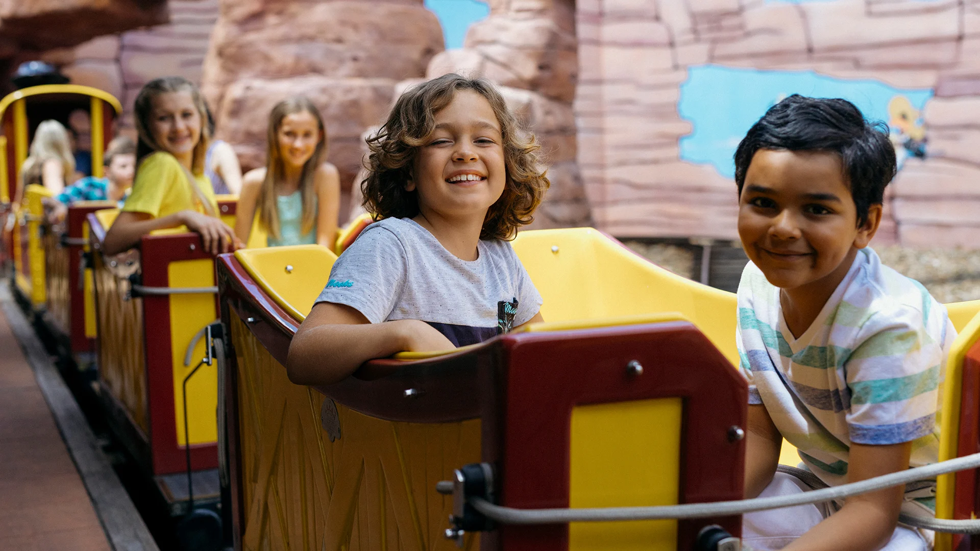 Children laughing and having fun on the Yosemite Sam Railroad kids ride at Warner Bros. Movie World, with a colorful train and playful expressions, capturing the joy and excitement of the theme park experience for kids