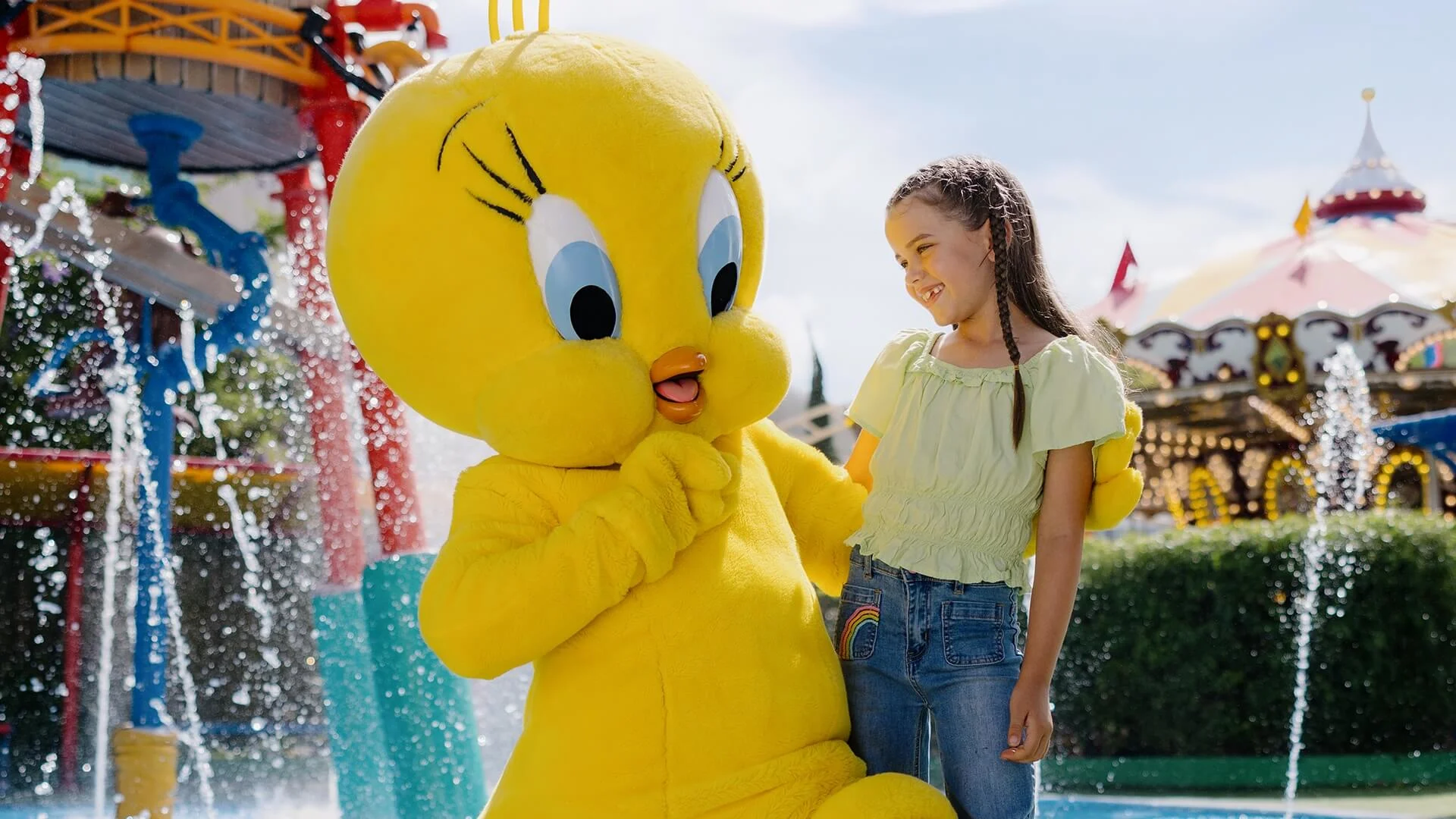 Tweety Bird posing for a photo with a young girl in front of the Splash Zone in Kids WB! Fun Zone at Warner Bros. Movie World