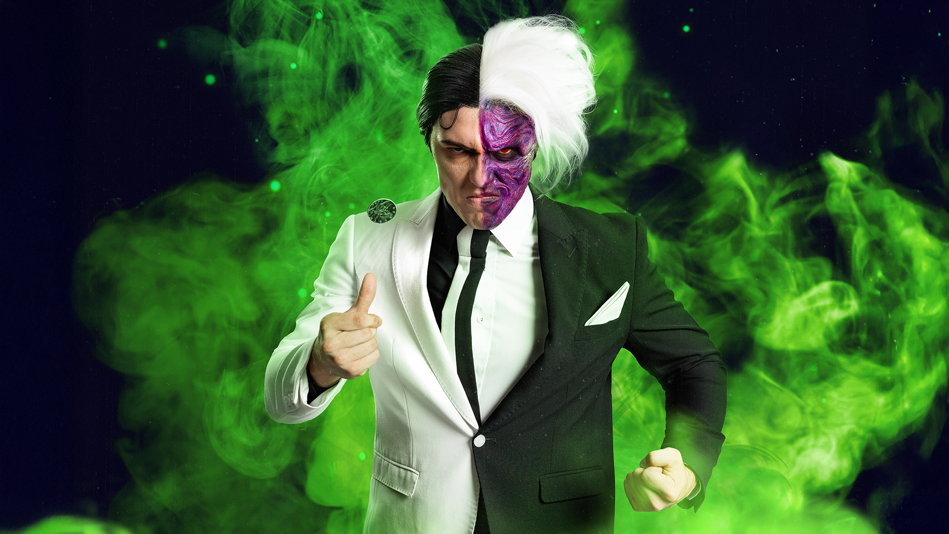 A person dressed as Two-Face from Batman, wearing a suit split into black and white halves, with one side of their face painted purple and scarred, surrounded by green smoke.