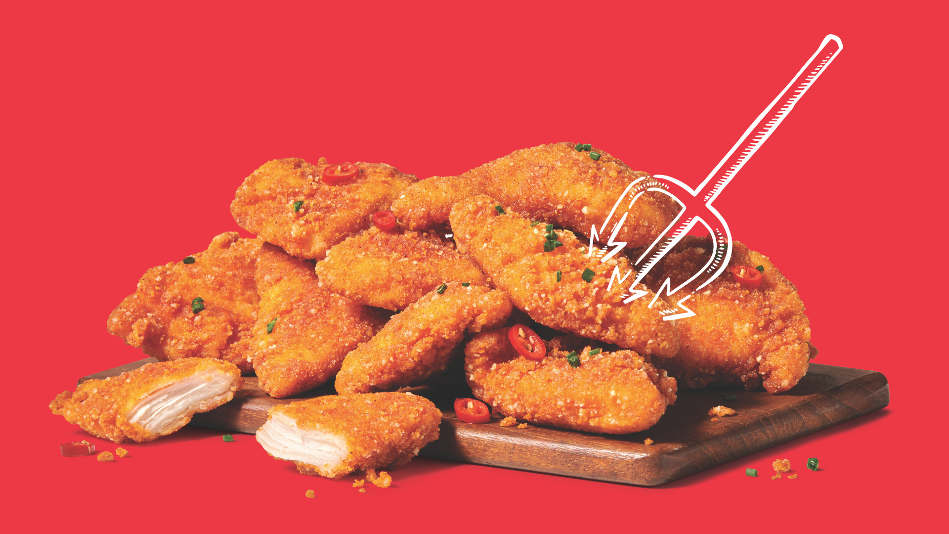 A stack of crispy, breaded chicken tenders garnished with herbs and sliced red chili peppers sits on a wooden board against a red background, with a white cartoon pitchfork illustration pointing at them.