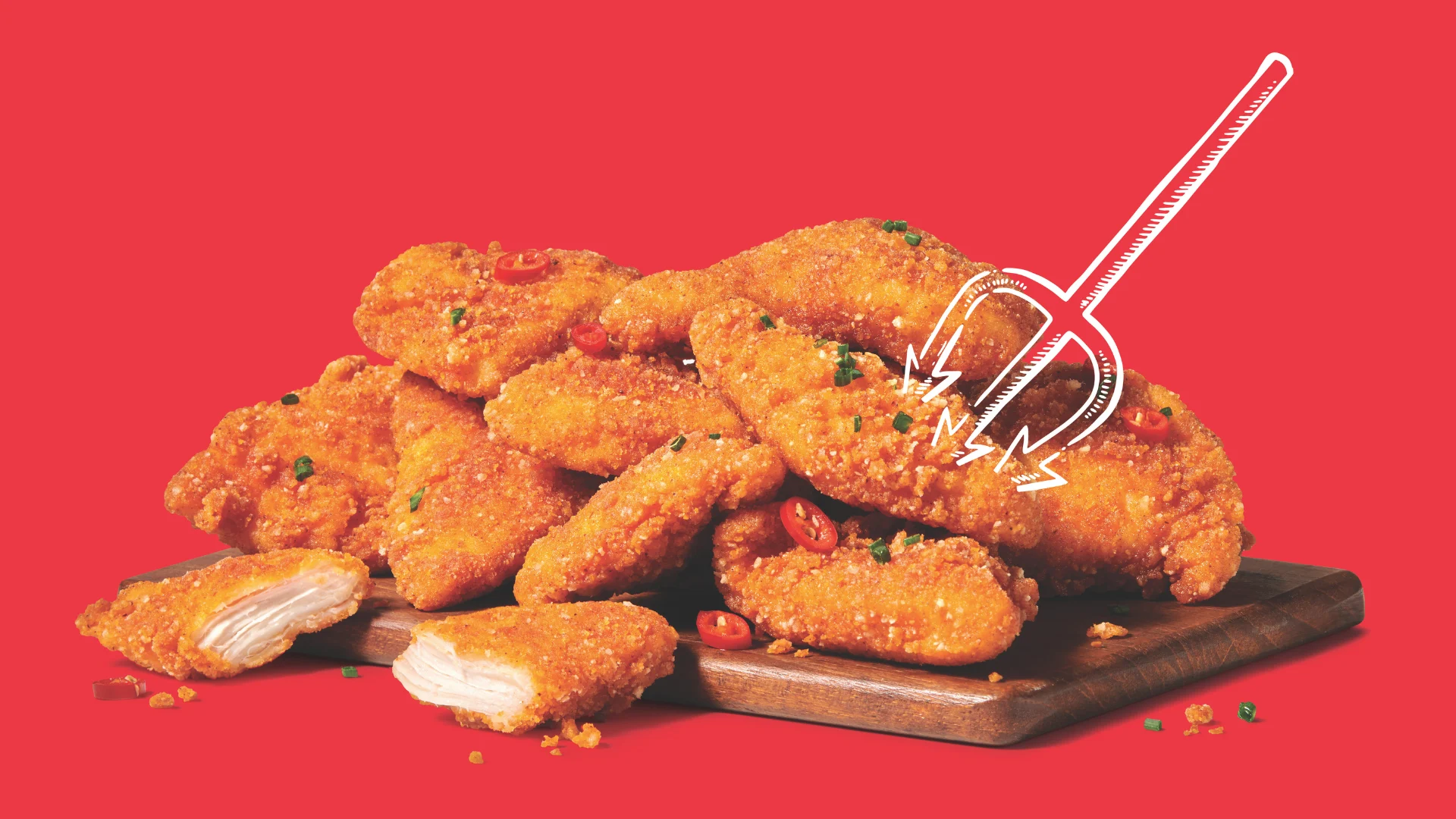 A stack of crispy, breaded chicken tenders garnished with herbs and sliced red chili peppers sits on a wooden board against a red background, with a white cartoon pitchfork illustration pointing at them.