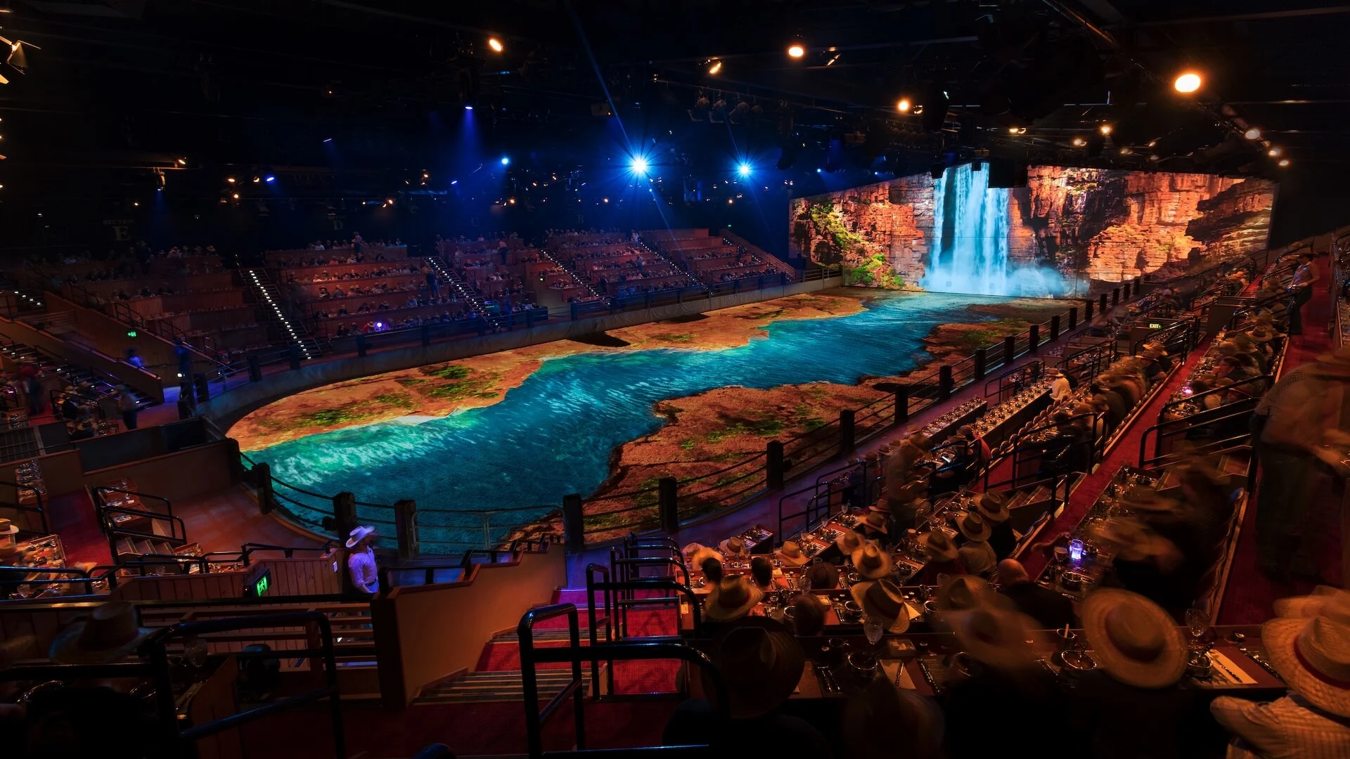 Immersive Australian Outback Spectacular arena with stunning projection-mapped river and waterfall scene as diners watch the show.
