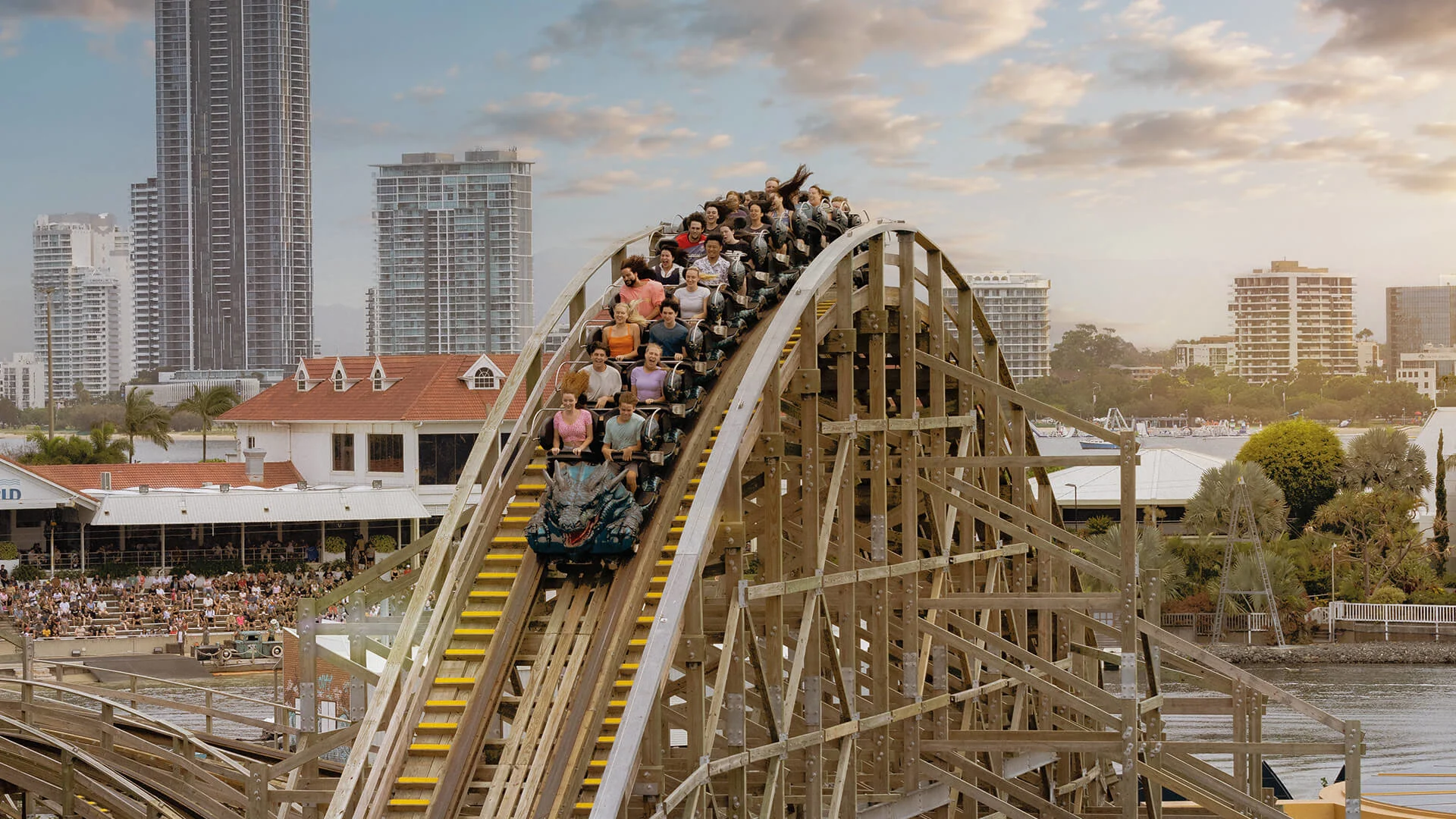 Visitors riding the Leviathan wooden roller coaster at Sea World Gold Coast, with city skyscrapers and Broadwater views in the background.