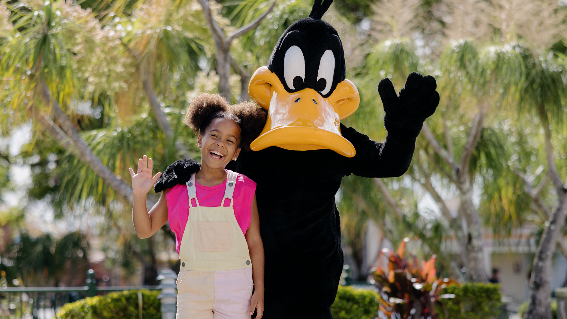 Daffy Duck and a young girl waving joyfully to the camera at Warner Bros. Movie World