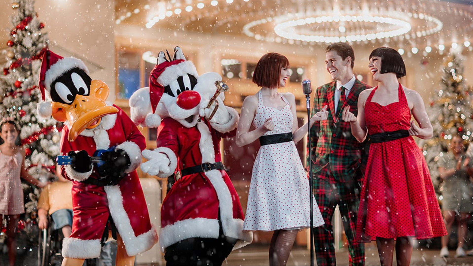 Daffy Duck and Sylvester dressed as Santa stand with two women in vintage dresses and a man in a plaid suit, surrounded by Christmas trees and falling snow in a festive holiday setting.
