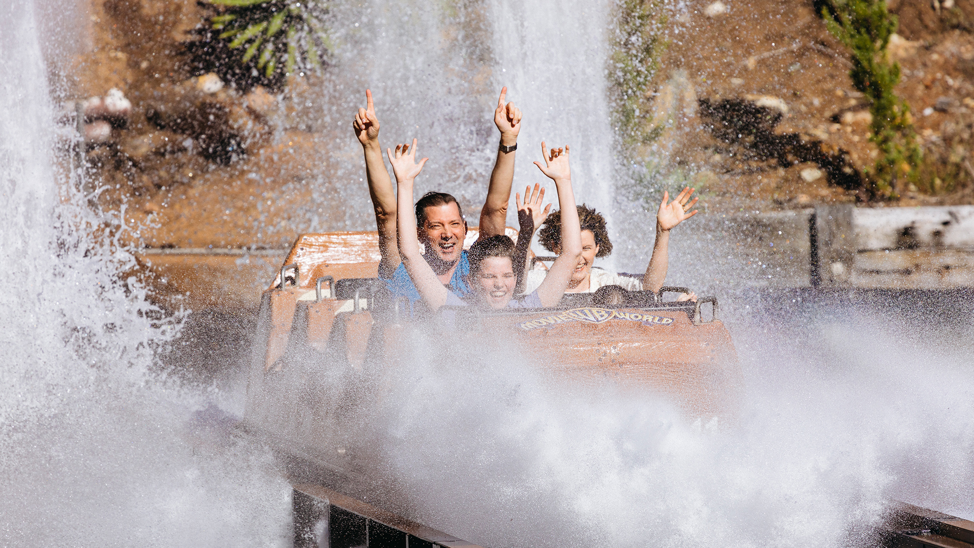 A family joyfully experiencing the Wild West Falls ride at Warner Bros. Movie World, with water splashing on them after the final exhilarating drop