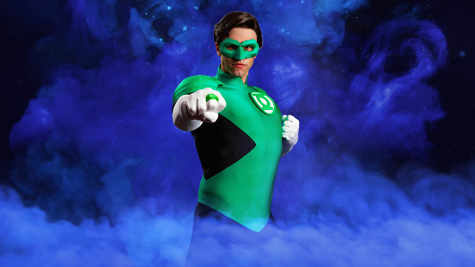 A person in a Green Lantern costume poses against a swirling purple background, extending a fist forward to display a green ring.