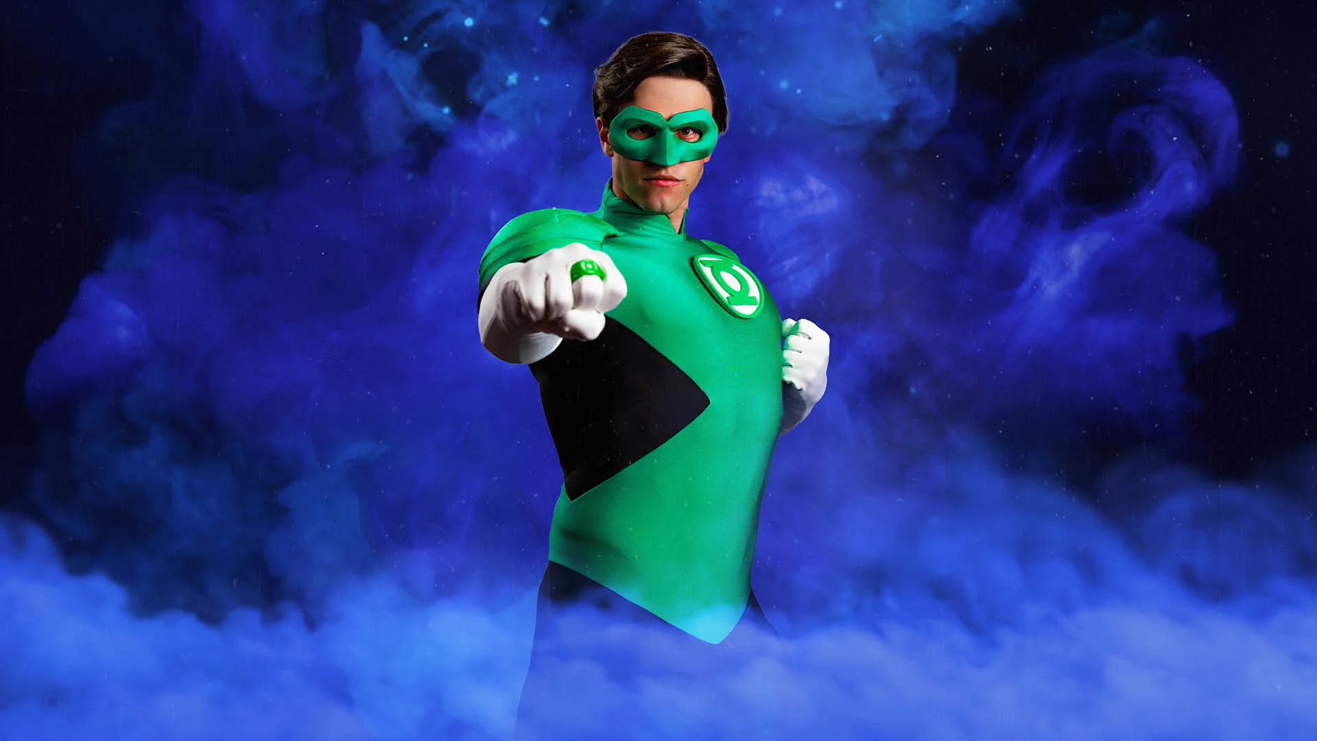 A person in a Green Lantern costume poses against a swirling purple background, extending a fist forward to display a green ring.