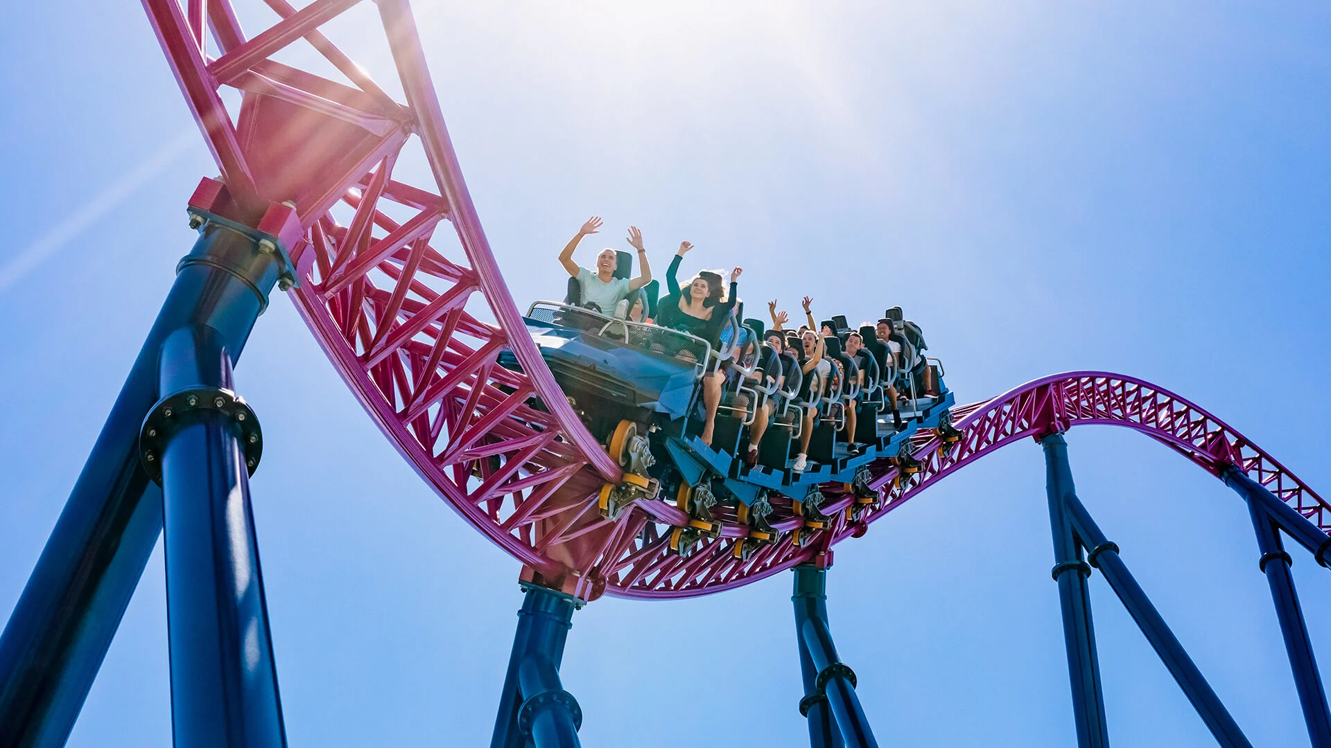 Excited riders with their hands up, enjoying the thrilling experience on the DC Rivals HyperCoaster at Warner Bros. Movie World, feeling the rush of high-speed twists and turns