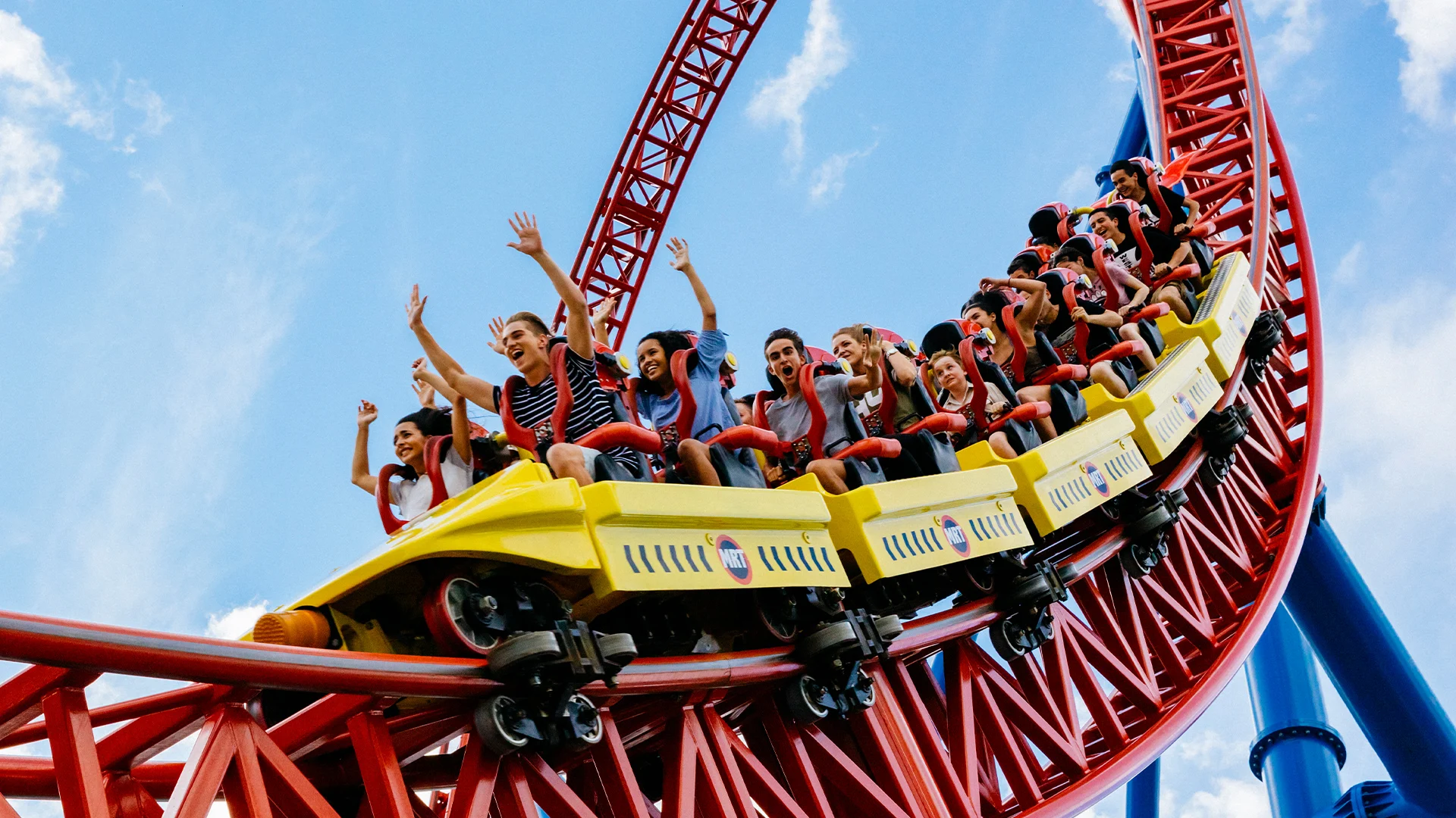 Excited riders experiencing the thrilling Superman Escape ride at Warner Bros. Movie World, with high-speed twists and turns against a backdrop of blue sky
