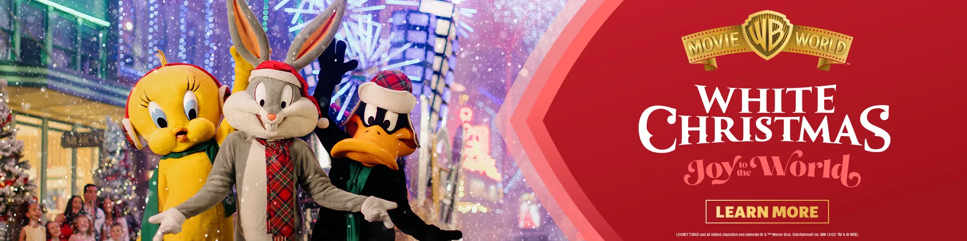 Bugs Bunny, Tweety Bird, and Daffy Duck dressed in festive winter scarves and hats pose on a snowy, decorated street next to a red banner reading "White Christmas Joy to the World, Movie World.