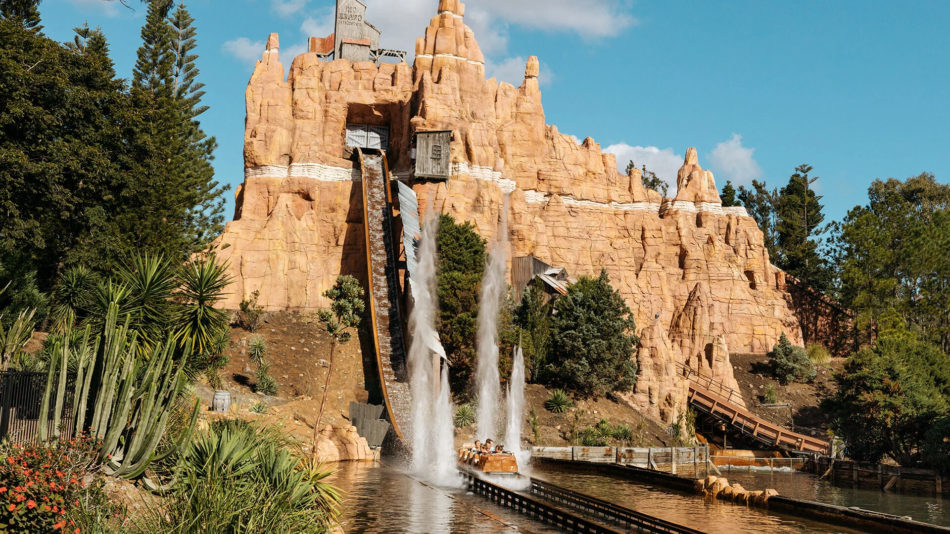 Excited riders getting splashed at the bottom of the hill on the Wild West Falls Adventure Ride at Warner Bros. Movie World, with water effects adding to the thrill and excitement of the experience