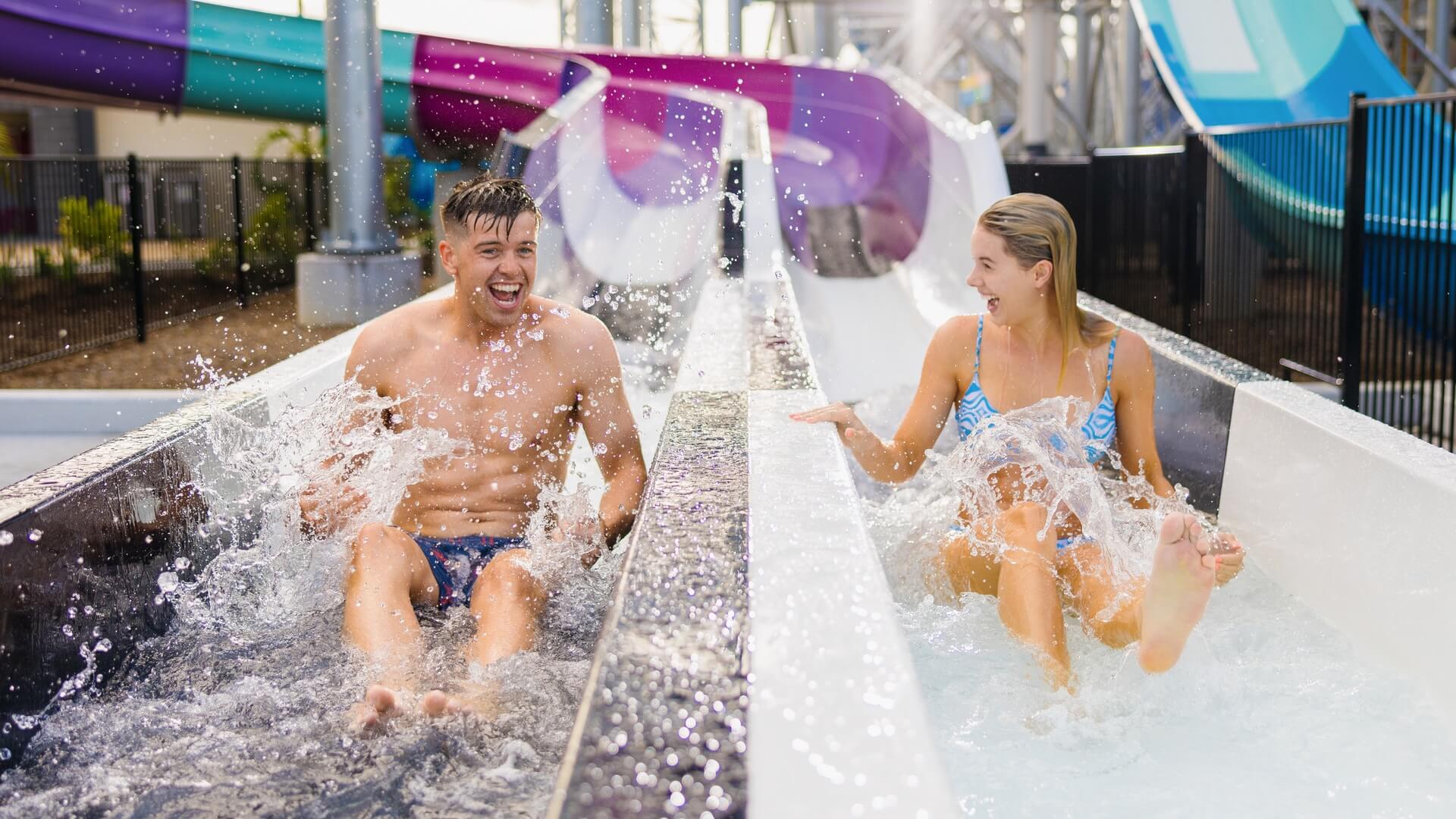 Friends splashing and laughing as they race side by side down the Super Ripper water slides at Wet’n’Wild.