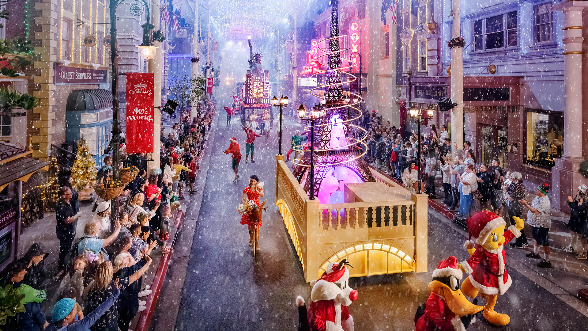 A festive parade moves down a snow-covered street lined with cheering crowds, colorful floats, performers in costume, and bright holiday lights, creating a joyful holiday atmosphere.
