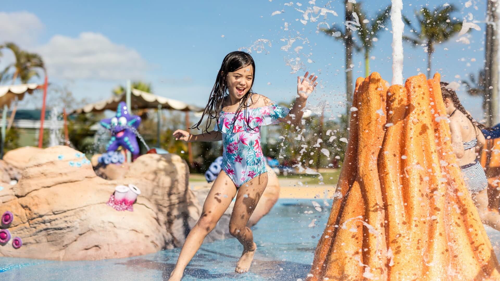 Young girl playing and splashing in the Castaway Bay water park at Sea World Gold Coast on a sunny day.