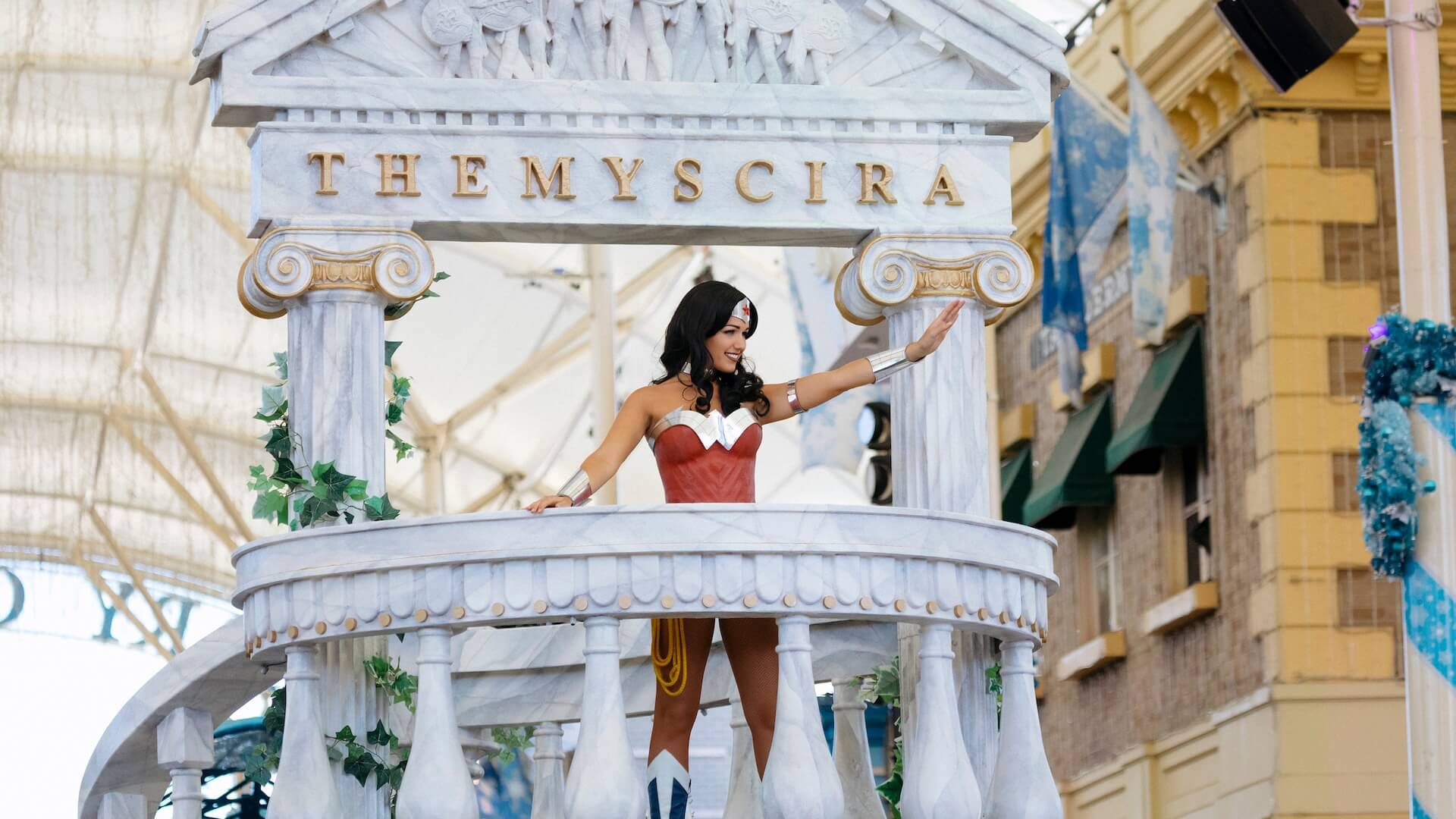 Wonder Woman standing on a float and waving to the crowd during the Star Parade at Warner Bros. Movie World, adding superhero charm and excitement to the parade